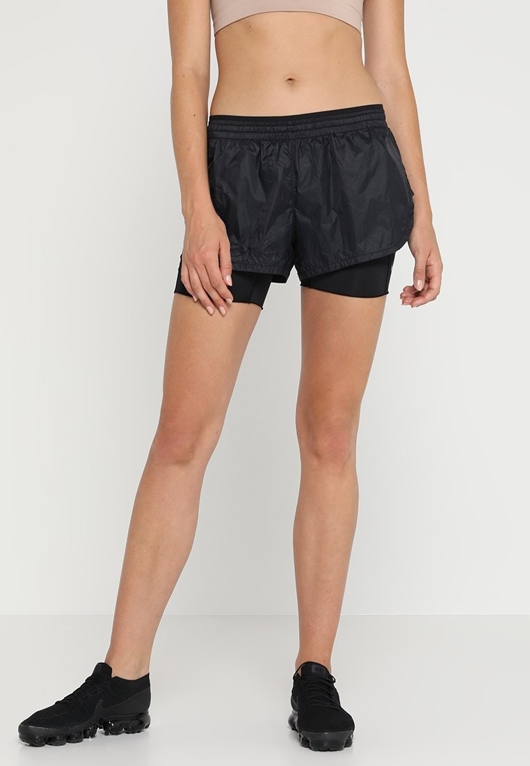 Svarta idrottsshorts i ett lätt, strukturerat tyg med resårmidja, lager på lager över åtsittande svarta shorts.