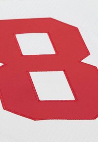 Red number 8 stitched on white breathable sports fabric, showing texture and detail of the stitching edges.