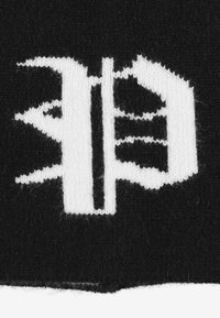 Czarna tkanina z wyraźnym białym wzorem graficznym zawierającym zintegrowane kształty i linie, w tym stylizowaną literę oraz abstrakcyjne elementy.