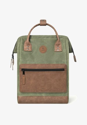 Grüner Stoffrucksack mit braunen Kunstlederakzenten, einem oberen Griff, einer vorderen Reißverschlusstasche und einem rundem Logopatch. Strukturierte Oberflächen sind vorhanden.