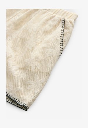 Kreem värvi lühikesed püksid, millel on tekstureeritud palmilehe muster. Elastsest materjalist vöökoht ja kontrastsed mustad õmblused õmblusel. Kerge materjal.