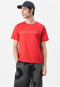 T-shirt rossa in cotone con maniche corte e collo rotondo, con il logo "marimekko" in testo grigio chiaro sul petto.