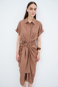 Abito camicia marrone a maniche corte con bottoni frontali e vita legata. Tessuto morbido, lunghezza al ginocchio con dettagli drappeggiati e spacco laterale.