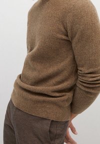 Suéter de punto marrón con tejido texturizado, puños y dobladillo acanalados. Combinado con pantalones marrones de cuadros. Diseño simple y ajustado.
