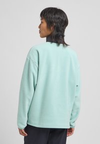 Light mint green fleece sweatshirt with a relaxed fit, round neckline, and dropped shoulders; features textured material and ribbed accents.