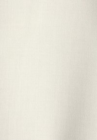 Tissu beige clair avec une surface lisse et légèrement texturée. Couleur uniforme sans motifs ni accents visibles.