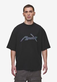 Black oversized t-shirt made from cotton, featuring a large gradient logo in the center. The design has short sleeves and a crew neckline.