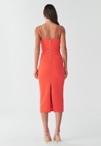 Oranges Midi-Kleid mit Spaghettiträgern, Reißverschluss auf der Rückseite und Schlitz im Rücken. Glatte Textur und strukturiertes Design.