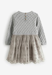 Robe en tricot grise à manches longues, avec un haut texturé et une jupe en tulle beige clair brodé, terminée par trois boutons au dos.