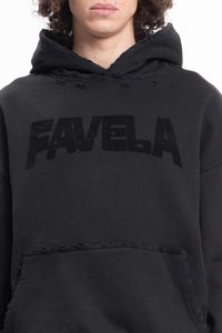 Osoba ubrana w czarną bluzę z kapturem o postrzępionych brzegach, z napisem "FAVELA" w dużych, pogrubionych, lekko zniszczonych literach na piersi.