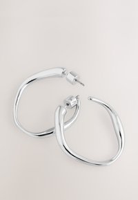 Silver hoop earrings with a smooth, rounded design, featuring a slightly textured finish and secure post-back closure.