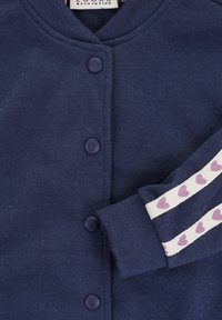 Marineblauwe sweatshirts met een ronde halslijn, voorzien van paarse knopen en witte mouwen met een patroon van paarse hartjes. Zachte textuur, casual ontwerp.