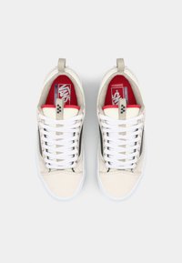 Beige lærstoff sneakers med hvite snører, polstret krage og rød innside. Har en svart sidestrek og hvit gummisåle.