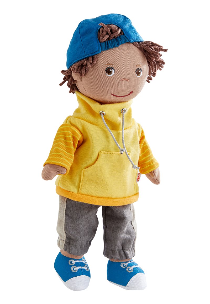 Soft doll with brown yarn hair wearing blue cap backwards, yellow hoodie with striped sleeves, gray pants, and blue sneakers.