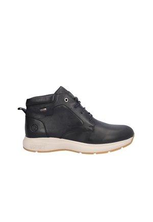 Bota de tobillo de cuero negro con suela blanca, cierre de cordones delante y tira para tirar en el talón, diseñada para uso casual o al aire libre.