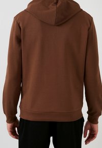 Sudadera con capucha marrón, con una capucha y mangas de textura acanalada. El cuerpo es liso y presenta un dobladillo y puños acanalados.
