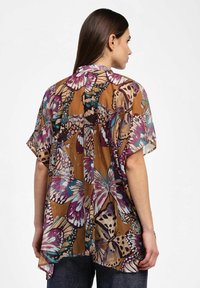 Leggera blusa stile kimono marrone con ampi motivi di farfalle in viola, verde teal e crema; design morbido con maniche corte e orlo curvo.