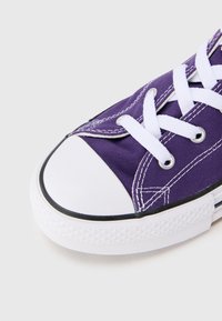 Μοβ πάνινο αθλητικό παπούτσι με λευκά κορδόνια, λαστιχένιο κάλυμμα δακτύλων και μαύρο περίγραμμα. Διαθέτει ραμμένες λεπτομέρειες και υφή στη σόλα για καλύτερη πρόσφυση.