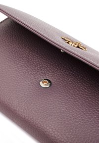 Clutch in pelle viola con texture, accentuato da un motivo coccodrillo in tonalità oro e chiusura a scatto magnetico. Presenta un interno liscio.