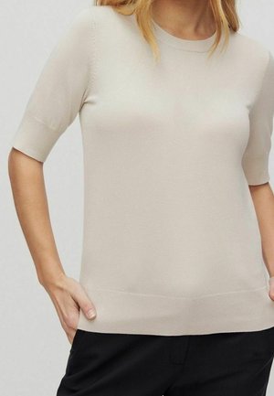 Top a maniche corte di maglia beige chiaro con scollatura rotonda e orlo a costine. Texture liscia con silhouette aderente.