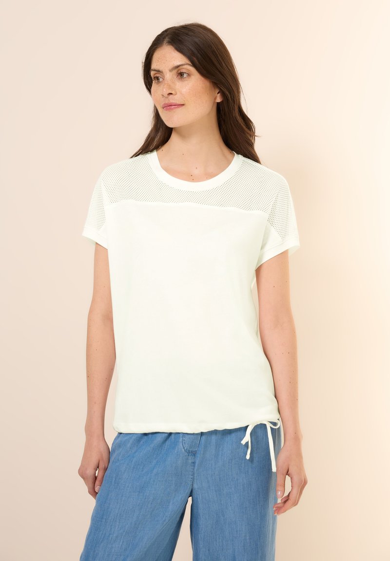 T-shirt léger en crème à manches courtes avec un panneau supérieur en maille, un col rond et un cordon de serrage ajustable à l'ourlet. Tissu doux et coupe décontractée.