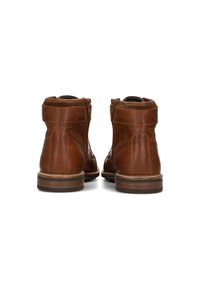 Botas de tobillo de cuero marrón con una textura suave, puntera redondeada y tacón de madera bajo. Presentan una cremallera lateral y detalles de costura.