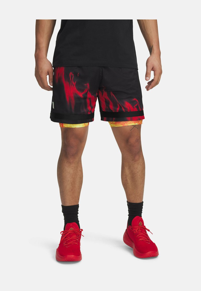 Pantaloni corti in rete nera con un motivo a fiamma rossa, accenti gialli all'orlo e strisce orizzontali nere in contrasto. Sneakers rosse e calzini.