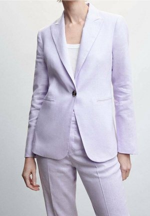 Mujer con blazer sastre lavanda claro con un botón abrochado y pantalones a juego, sobre una camiseta blanca acanalada.