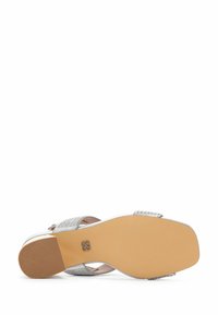 Sandale argentée avec un design de bride texturée et une semelle beige lisse. Présente des brides réglables pour un ajustement parfait. Profil de talon plat.