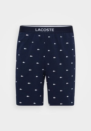 Navy blue boxer shorts with a soft texture, featuring a white Lacoste logo waistband and small white crocodile patterns throughout.