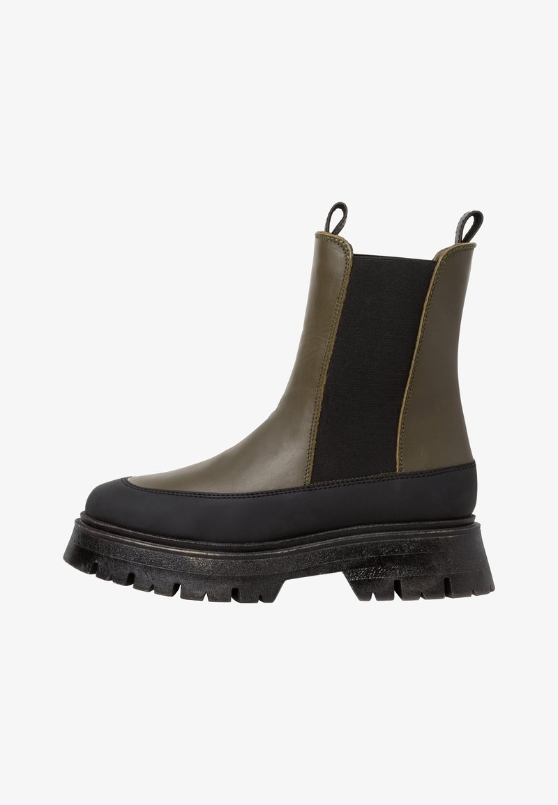 Bottes Chelsea avec une tige en cuir vert olive, des panneaux latéraux élastiques noirs, et une semelle noire texturée et épaisse. Tirettes à l'arrière.