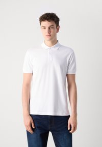 Hvit polo-skjorte laget av glatt stoff, med klassisk krage og tre knapper, med en liten logo brodert på brystet.