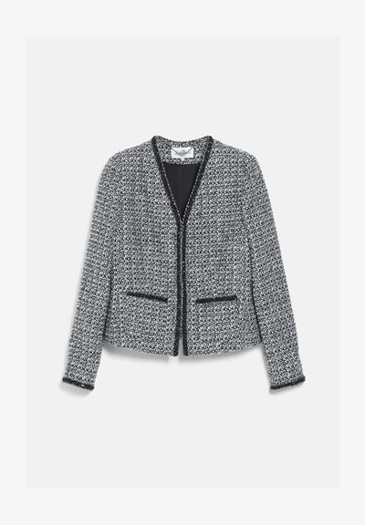 Veste en tweed noir et blanc à manches longues, devant ouvert, deux petites poches avant et bordures noires le long des bords et des poignets.