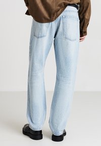 Jeans di denim blu chiaro con una vestibilità rilassata, caratterizzati da un design a gamba dritta e cinque tasche. Completati con calzature nere.