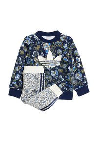 Tamsiai mėlynas megztinis su gėlių raštu ir baltu Adidas logotipu, derinamas su panašių raštų kelnėmis, turinčiomis baltus akcentus ant rankogalių.