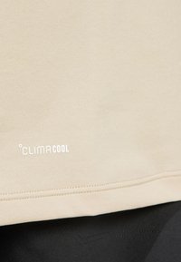 Beige T-shirt with "CLIMACOOL" logo in white, featuring a smooth texture and simple design, with visible stitching at the hem.