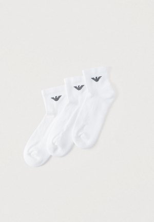 Calzini alla caviglia in cotone bianco, confezione da tre. Ogni calzino presenta un logo nero sul polsino, una texture a coste e una finitura liscia.