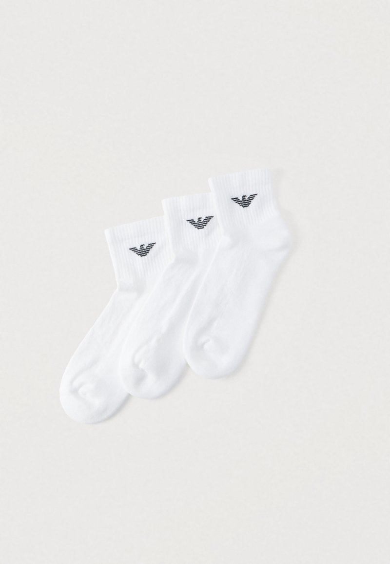 Calcetines tobilleros de algodón blanco en un pack de tres. Cada calcetín presenta un logo negro en el puño, textura acanalada y acabado liso.