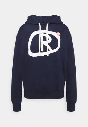 Laivastonsininen huppari, jossa valkoiset nyörit, suuri valkoinen graafinen "R" epäsäännöllisen soikion sisällä ja pieni punainen pyöreä logo rinnassa.