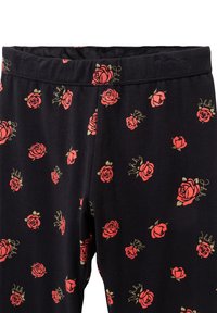 Leggings neri con un motivo ripetuto di rose rosse con accenti verdi e una sottile scritta dorata. Tessuto morbido e elasticizzato; vita elasticizzata.