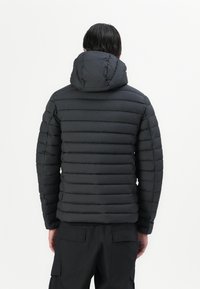 Sort pufferjakke med vandret quiltet design og hætte. Har en glat tekstur og slidstærkt stof. Synlige søm accenter.