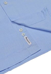 Hellblaues Hemd aus strukturiertem Stoff mit weißen Knöpfen und einem Etikett am Saum. Die Falten zeigen eine saubere Naht.