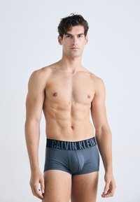 Graue Baumwoll-Stretch-Boxershorts mit einem schwarzen elastischen Bund, der mit dem "CALVIN KLEIN"-Logo versehen ist. Glatte Textur, figurbetontes Design.