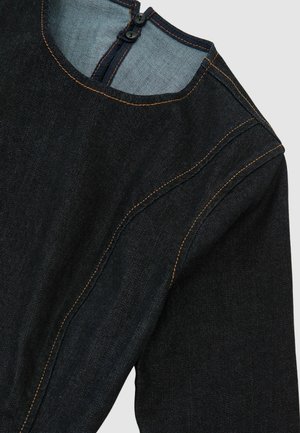 Tume teksariie kangas, millel on sile tekstuur ja nähtavad õmblused. Ümar kaelus tagumise tõmblukuga ning kontrastsete beežide niidiga detailid.