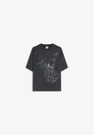T-shirt noir à manches courtes avec un graphisme en contour blanc représentant Spider-Man en pleine posture dynamique de balancement sur le devant.