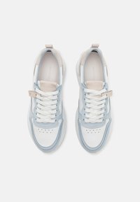 Des baskets avec un empeigne en cuir blanc agrémentée d'accents bleu clair, une semelle intermédiaire texturée et des lacets blancs. Petit logo sur la languette.