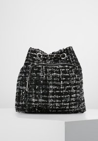 Sac en tissu tissé noir et argent avec une fermeture à cordon, comportant une poche zippée à l'avant et un accent en chaîne en haut.