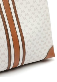 Vit canvasväska med ett diskret monogrammönster, med bruna läderdetaljer och två brunvita randiga inslag. Rundad botten.