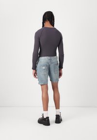 Långärmad grå ribbad topp som matchas med blekblå denimshorts, vilket visar en ren design. Svarta skor med tjocka sulor och vita strumpor.