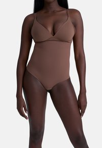 Body marrone con scollatura a V profonda e spalline regolabili. Texture liscia, design aderente e gambe alte.